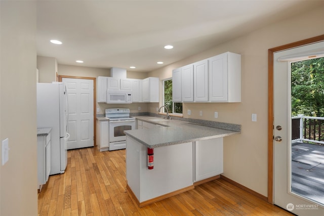 kitchen with a peninsula, white appliances, white cabinetry, light wood-style floors, and light countertops