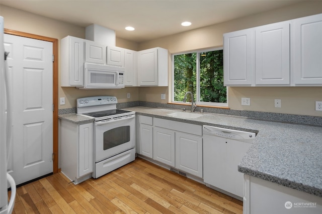 kitchen with white appliances, white cabinets, light wood-style floors, a sink, and recessed lighting