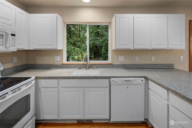 kitchen with white appliances, light stone counters, white cabinets, and a sink