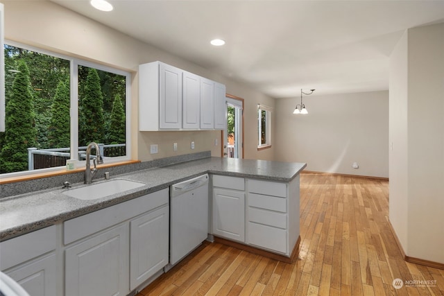 kitchen featuring a peninsula, white dishwasher, white cabinetry, and a sink