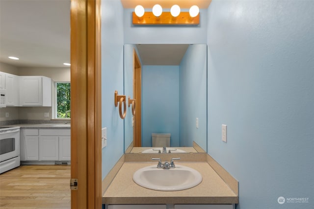 bathroom with toilet, recessed lighting, wood finished floors, and vanity