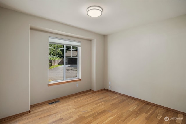 spare room featuring light wood-style floors, baseboards, and visible vents