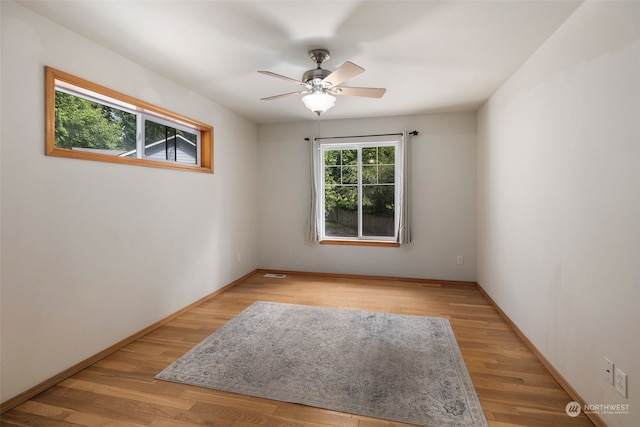 spare room featuring light wood finished floors, visible vents, baseboards, and a ceiling fan