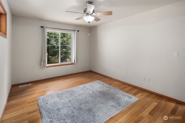 spare room featuring light wood finished floors, visible vents, and baseboards