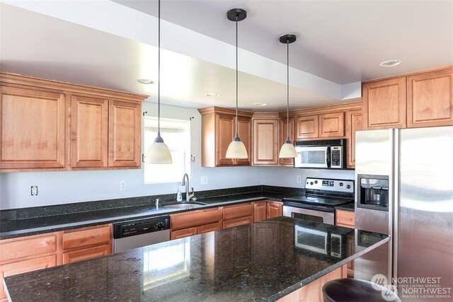 kitchen featuring dark stone countertops, appliances with stainless steel finishes, and pendant lighting