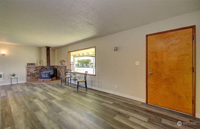 living room featuring hardwood / wood-style flooring, a wood stove, and a textured ceiling