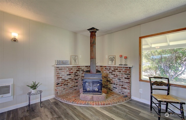 living room featuring heating unit, hardwood / wood-style flooring, a textured ceiling, and a wood stove