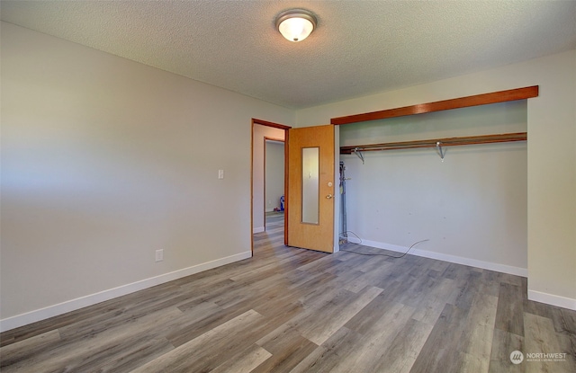 unfurnished bedroom featuring a closet, light hardwood / wood-style flooring, and a textured ceiling