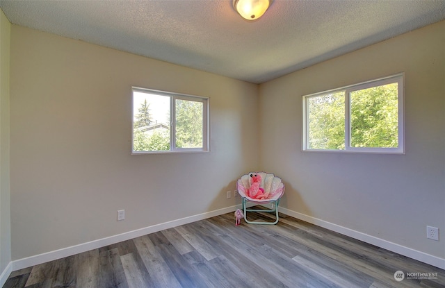 unfurnished room with hardwood / wood-style flooring, plenty of natural light, and a textured ceiling