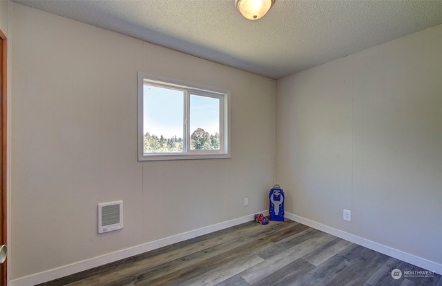 empty room with hardwood / wood-style flooring and a textured ceiling