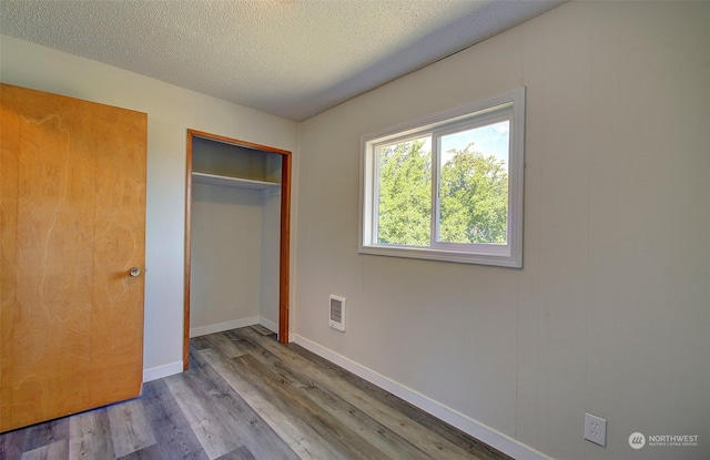 unfurnished bedroom with a closet, a textured ceiling, and light wood-type flooring