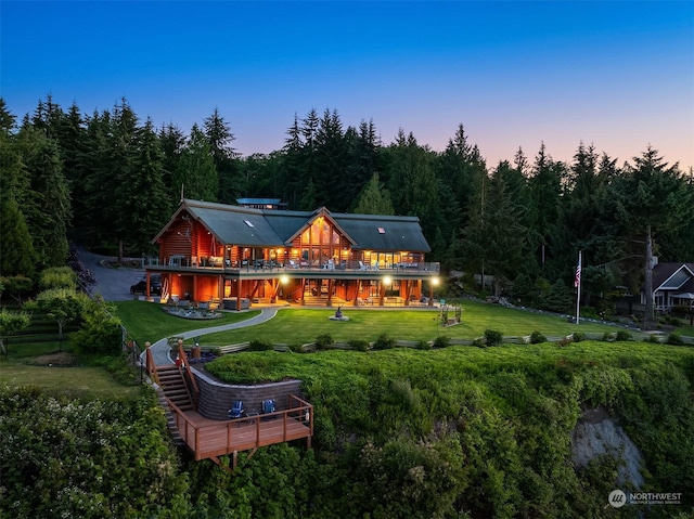 back house at dusk with a yard and a wooden deck