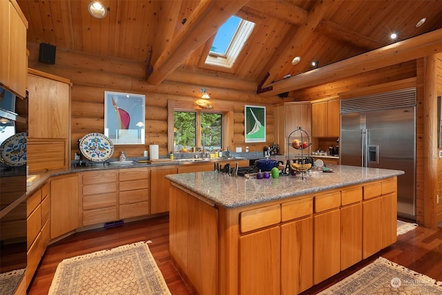 kitchen featuring dark wood-type flooring, a skylight, log walls, a kitchen island, and stainless steel built in refrigerator