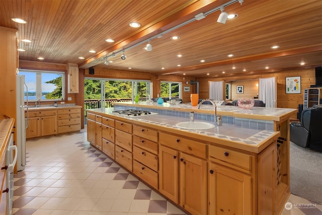 kitchen with wood ceiling, sink, white refrigerator, a kitchen island, and tile counters