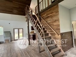 staircase featuring wood ceiling, wood walls, wood-type flooring, and a towering ceiling