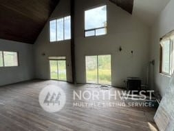 unfurnished living room featuring hardwood / wood-style floors, a wealth of natural light, and high vaulted ceiling