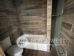 bathroom with toilet and tile walls