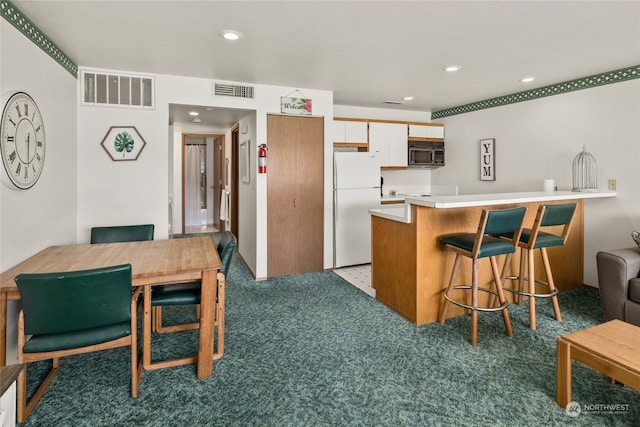 kitchen featuring white fridge, a breakfast bar, carpet floors, and kitchen peninsula