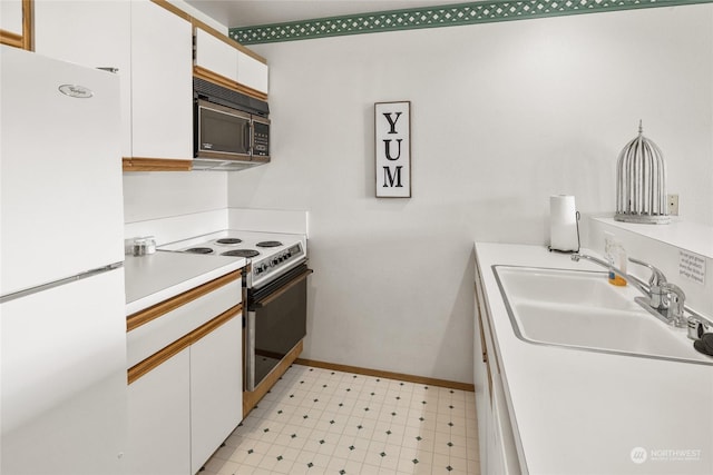 kitchen featuring black microwave, freestanding refrigerator, light floors, a sink, and electric range oven