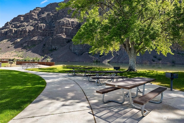 surrounding community with a patio, a water and mountain view, and a lawn