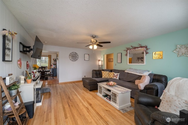 living room featuring ceiling fan, a textured ceiling, and light wood-type flooring