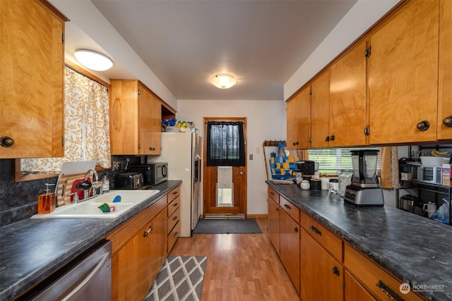 kitchen featuring tasteful backsplash, stainless steel appliances, sink, and light hardwood / wood-style flooring