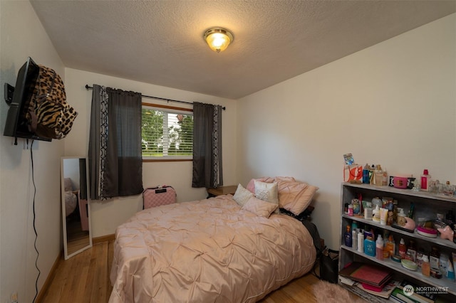 bedroom with light hardwood / wood-style flooring and a textured ceiling