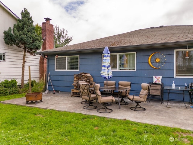 rear view of house featuring a yard, a patio area, and an outdoor fire pit