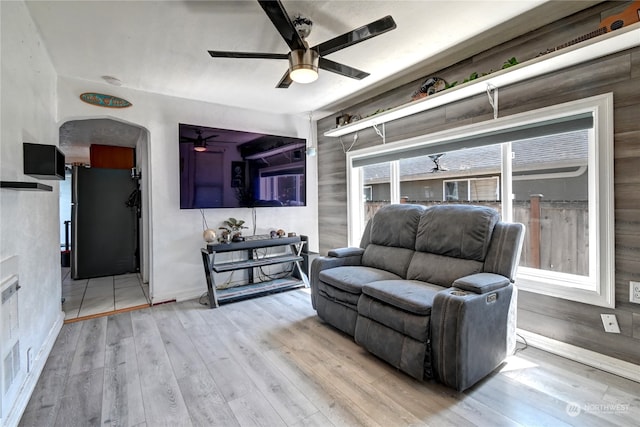 living room with wood walls, light hardwood / wood-style flooring, and ceiling fan