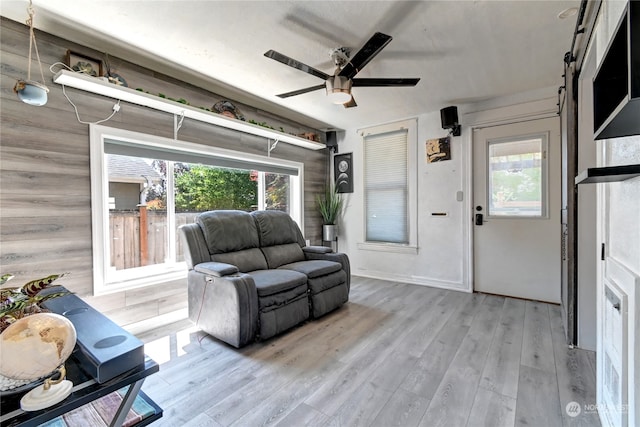 living room featuring a barn door, wood-type flooring, and ceiling fan