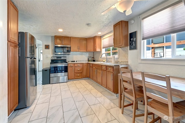 kitchen with tasteful backsplash, appliances with stainless steel finishes, light tile patterned floors, and ceiling fan