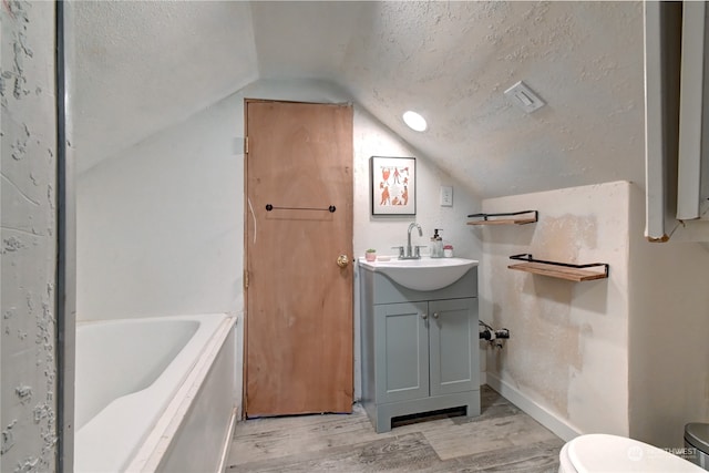 bathroom with vanity, wood-type flooring, toilet, a textured ceiling, and lofted ceiling