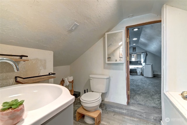 bathroom featuring a textured ceiling, toilet, vanity, hardwood / wood-style flooring, and vaulted ceiling