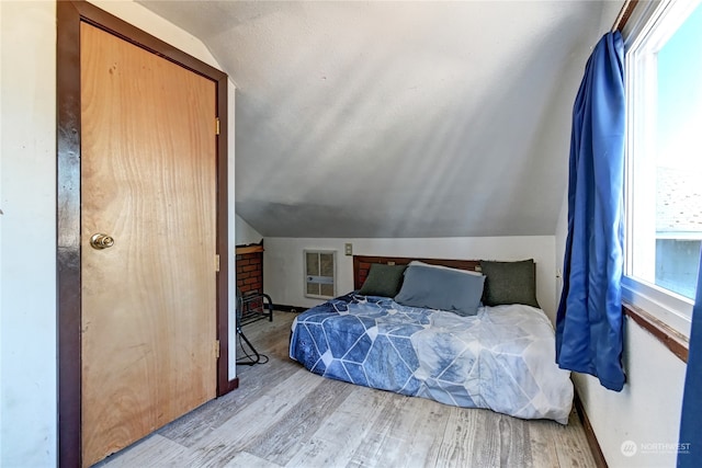 bedroom with a closet, lofted ceiling, and light wood-type flooring