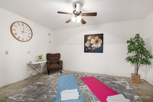 sitting room with ceiling fan and concrete flooring