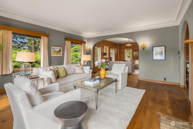 living area featuring crown molding, arched walkways, and dark wood-type flooring