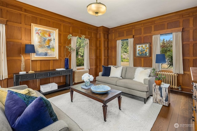 living area featuring radiator, wood walls, and dark wood-style flooring