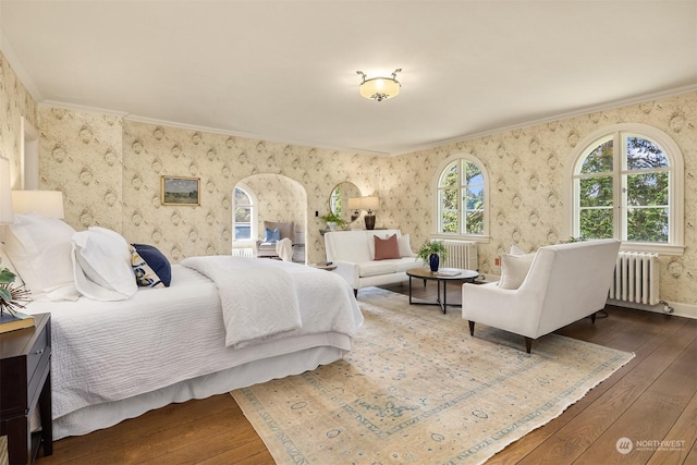 bedroom with wallpapered walls, dark wood-type flooring, and radiator