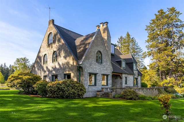 exterior space with a yard, a chimney, and stone siding