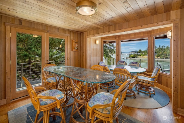 dining room featuring wood walls, wood ceiling, and light wood-style floors