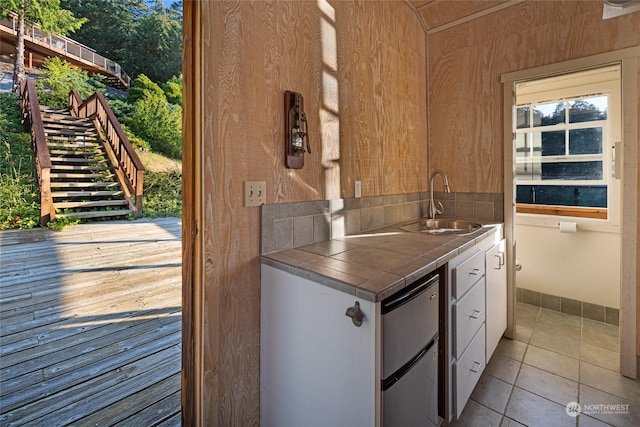 kitchen with tile countertops, a sink, white cabinets, fridge, and tile patterned floors