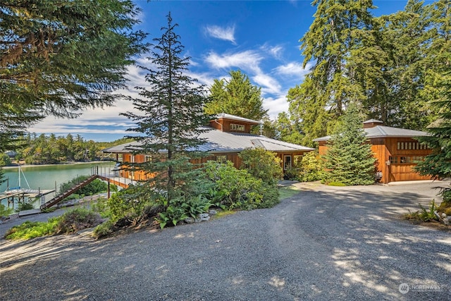 view of front of house with a boat dock, a water view, and metal roof