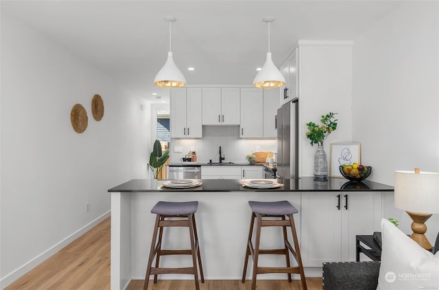 kitchen featuring decorative backsplash, stainless steel appliances, sink, white cabinets, and hanging light fixtures