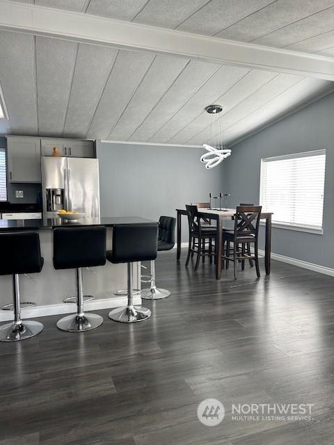 dining space featuring vaulted ceiling with beams, wood ceiling, and dark hardwood / wood-style floors