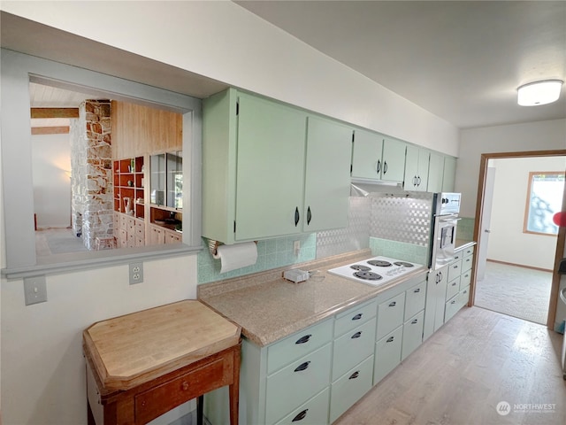 kitchen with stainless steel oven, tasteful backsplash, light hardwood / wood-style floors, and white electric cooktop