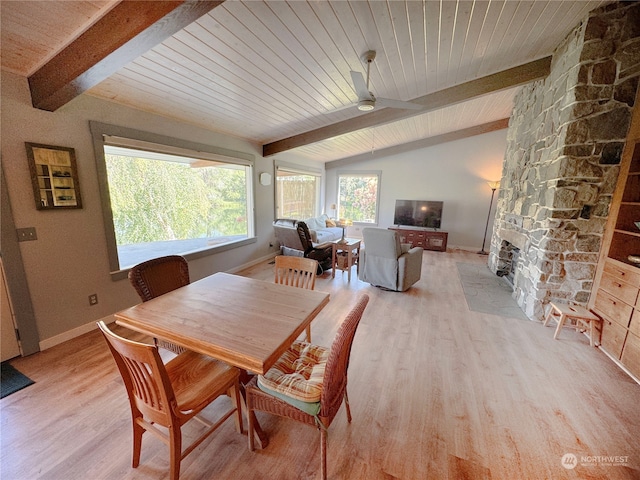 dining area with a stone fireplace, light hardwood / wood-style flooring, lofted ceiling with beams, and wood ceiling