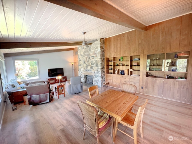 dining room featuring a stone fireplace, wooden ceiling, ceiling fan, and wood-type flooring