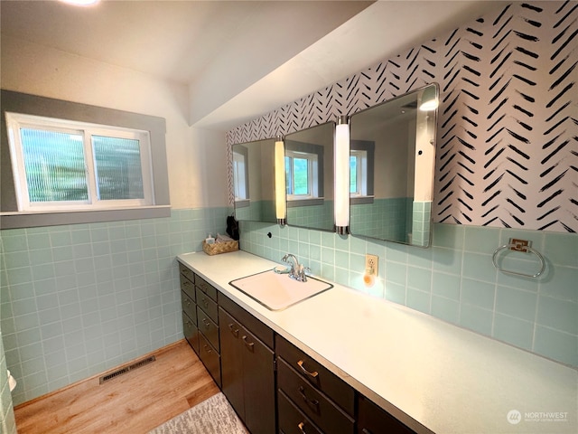 bathroom with tile walls, wood-type flooring, tasteful backsplash, and vanity