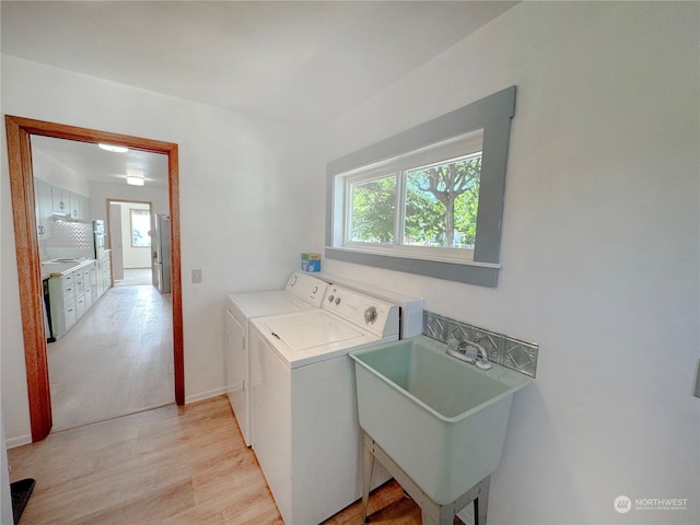 laundry area featuring washing machine and dryer, light hardwood / wood-style flooring, and sink