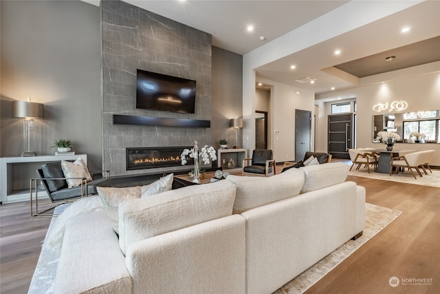 living room with light hardwood / wood-style floors, a large fireplace, and tile walls